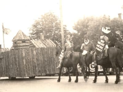 Tk’emlups te Secwepemc members ride on horseback carrying shields emblazoned with the message "we were here first" behind a replica of Fort Thompson in the city’s 1937 Dominion Day parade