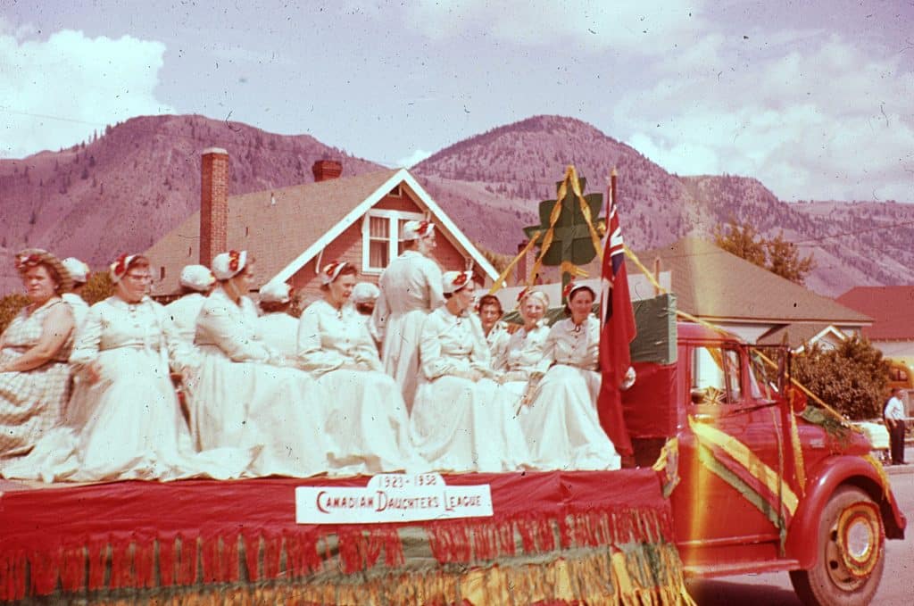 The Canadian Daughters League float features women in white dresses and bonnets in the 1958 Kamloops Dominion Day parade