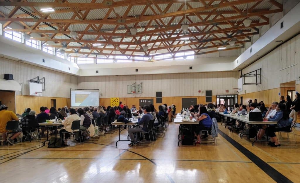 A gymnasium is filled with tables of language instructors for a sold out conference.