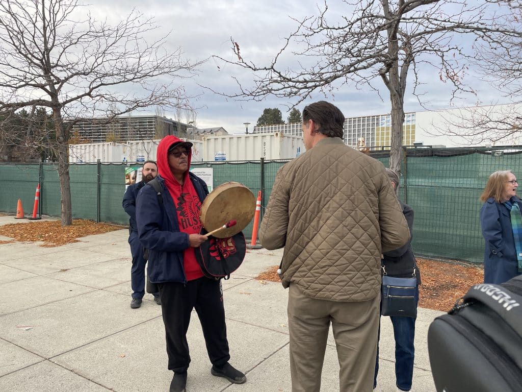 A drummer is actively drumming while a school denialist spoke. Kamloops residential school denialism