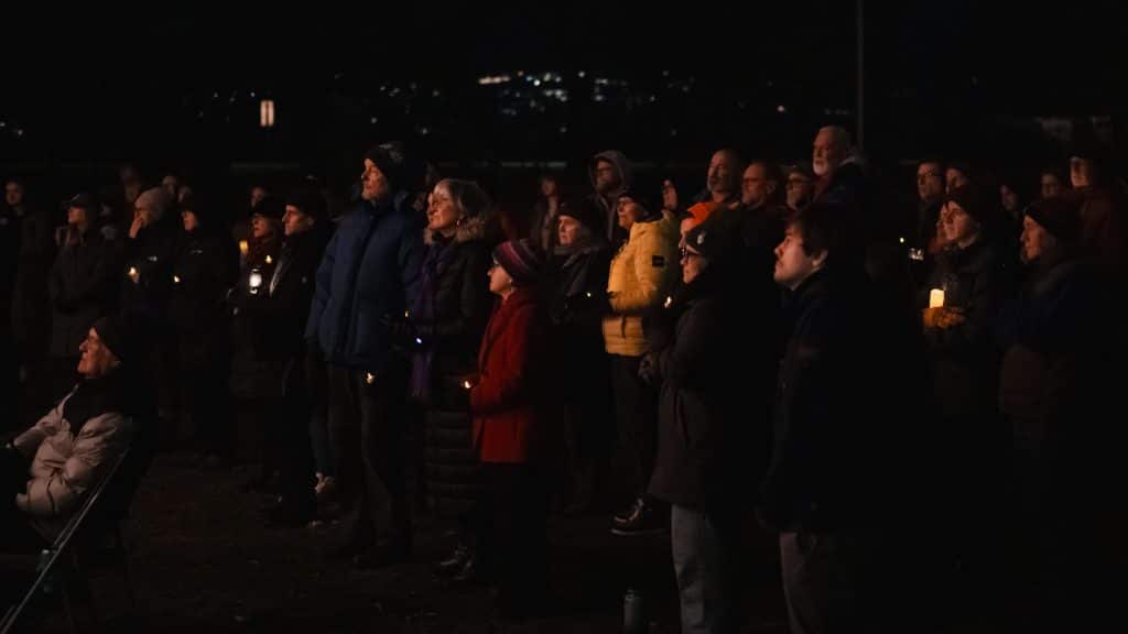 Kamloops community vigil for Muhammad “Ash” Zafar, where folks are holding candles together and watching the speech.