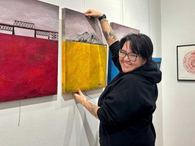 The DIS//CONNECT exhibition features art of all mediums. This photo has Paul hanging one of the art.