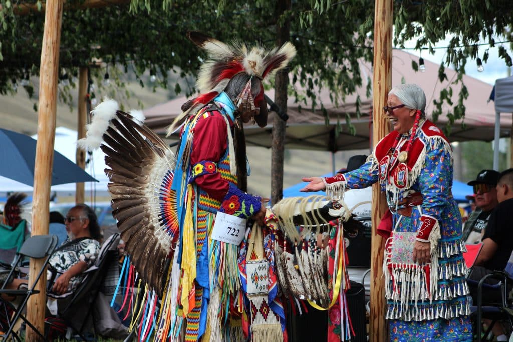 A men's traditional dancer stands with jingle dancer Adele Fletcher under the arbour for intertribals.